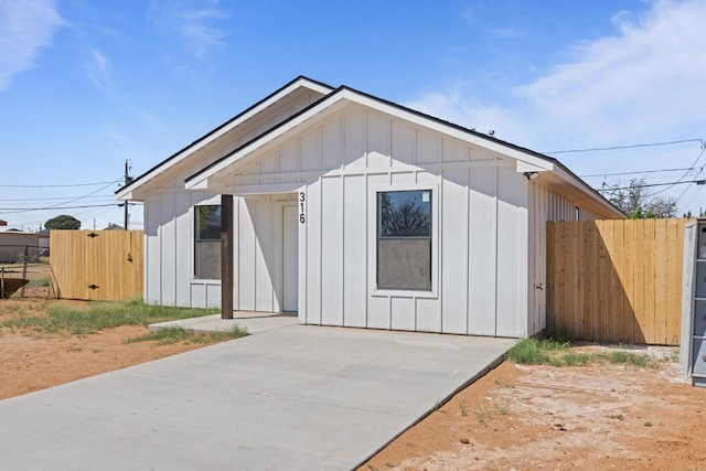 view of front facade featuring board and batten siding, a patio area, and fence