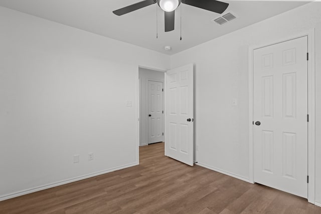 unfurnished bedroom featuring ceiling fan, baseboards, visible vents, and wood finished floors