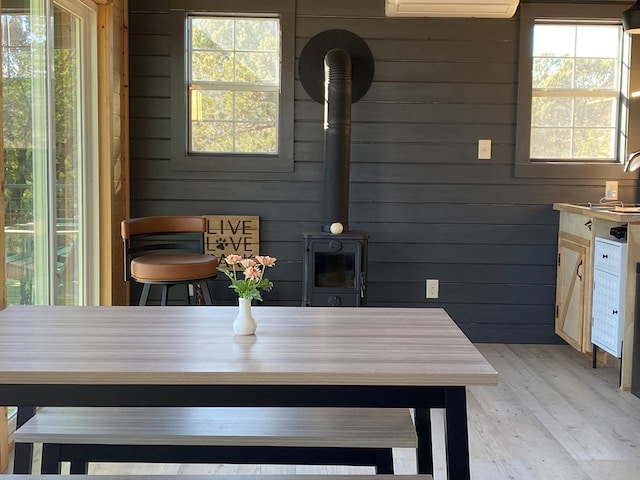 102 Low Meadow Pt, Fort Davis, TX 79734 - dining area with a wall unit AC, light wood-type flooring, wooden walls, and a wood stove