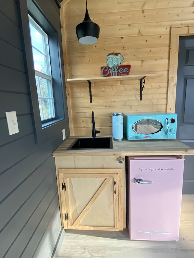 102 Low Meadow Pt, Fort Davis, TX 79734 - kitchen featuring a sink, wood walls, light countertops, dishwasher, and pendant lighting