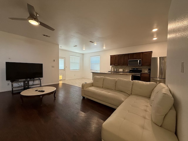 living area featuring visible vents, a ceiling fan, dark wood-style flooring, and baseboards