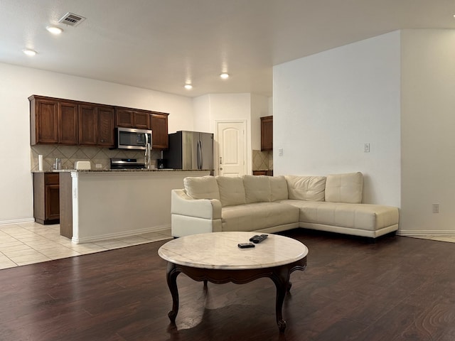living room with baseboards, light wood finished floors, and visible vents