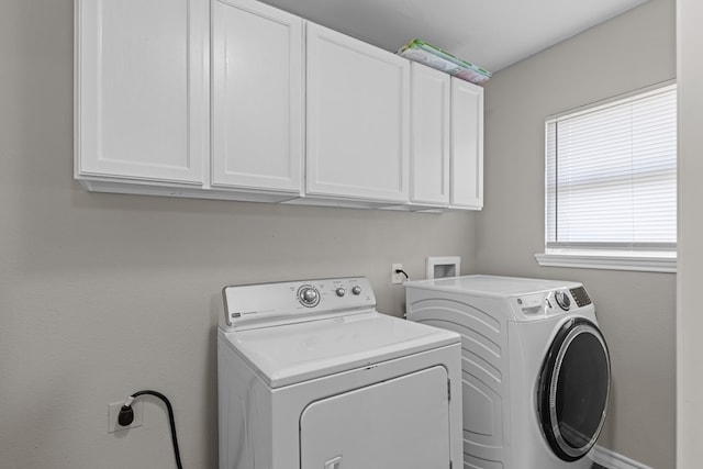 clothes washing area featuring cabinets and separate washer and dryer