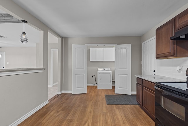 kitchen with black range with electric cooktop, dark brown cabinetry, wall chimney range hood, pendant lighting, and washer / clothes dryer