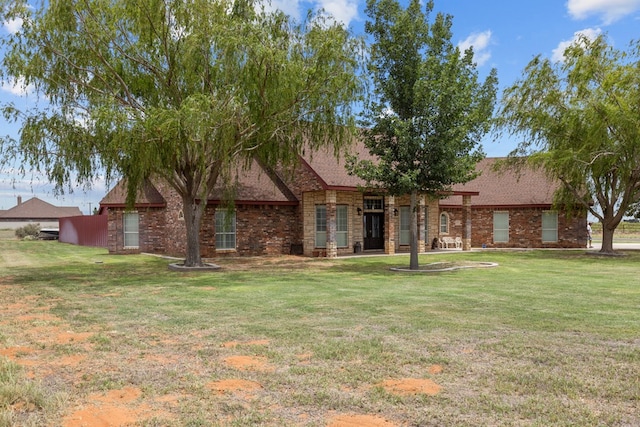 4975 SE 3000, Andrews, TX 79714 - view of front facade featuring stone siding, a front lawn, and roof with shingles