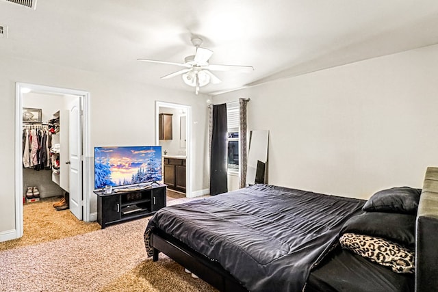 carpeted bedroom featuring ensuite bathroom, a walk in closet, ceiling fan, and a closet