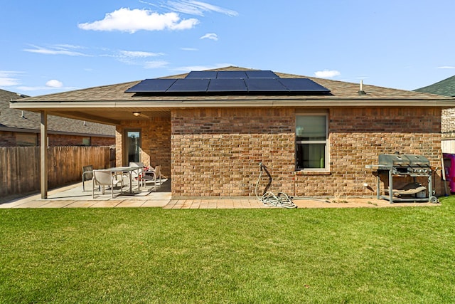 rear view of house featuring solar panels, a patio area, and a lawn