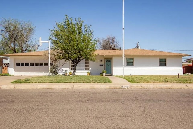 ranch-style home with an attached garage, concrete driveway, and a front yard