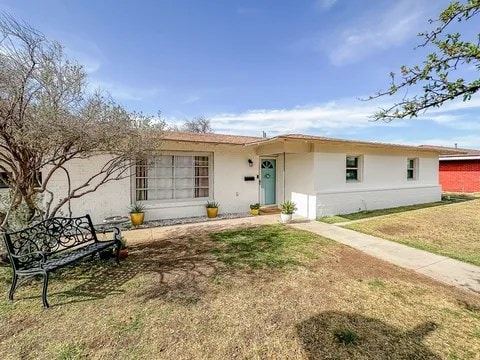 ranch-style house with a front lawn and stucco siding