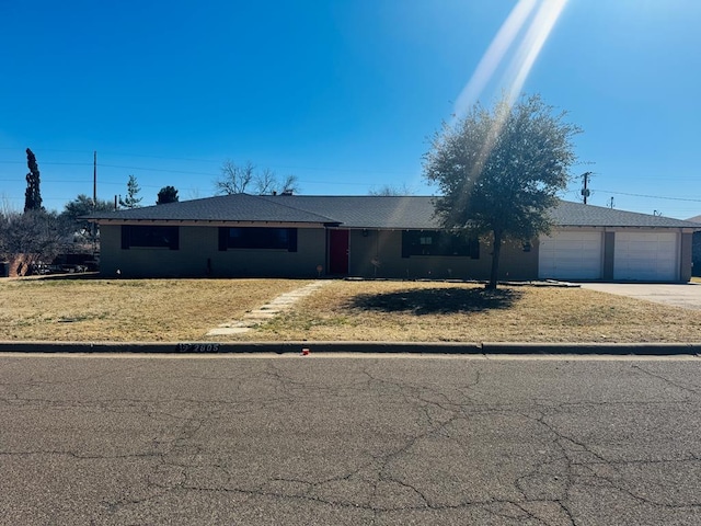 single story home with driveway, an attached garage, and a front lawn