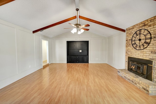 unfurnished living room featuring hardwood / wood-style flooring, a brick fireplace, vaulted ceiling with beams, and ceiling fan