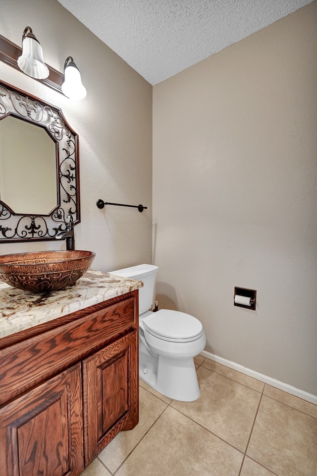 bathroom with vanity, toilet, tile patterned flooring, and a textured ceiling