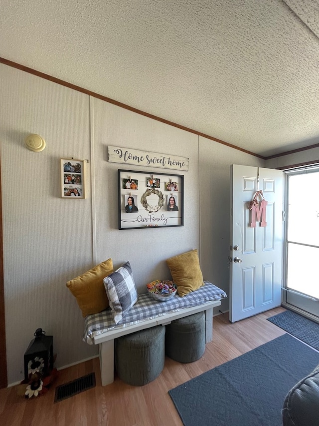 interior space featuring crown molding, light hardwood / wood-style flooring, and a textured ceiling