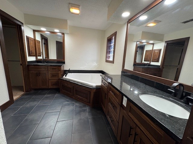 bathroom featuring vanity, a textured ceiling, and a bathing tub