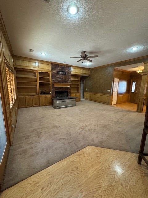 unfurnished living room featuring carpet, a fireplace, built in features, and a textured ceiling