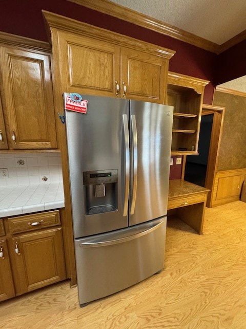 kitchen with tasteful backsplash, stainless steel fridge, tile counters, and crown molding