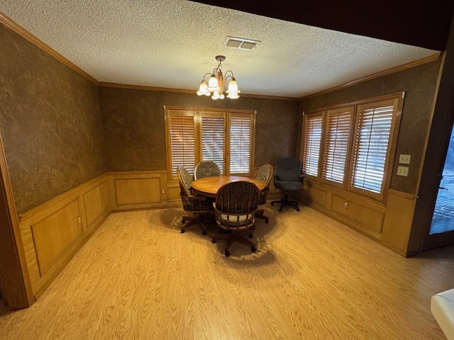 dining room with ornamental molding, light wood-type flooring, plenty of natural light, and a notable chandelier