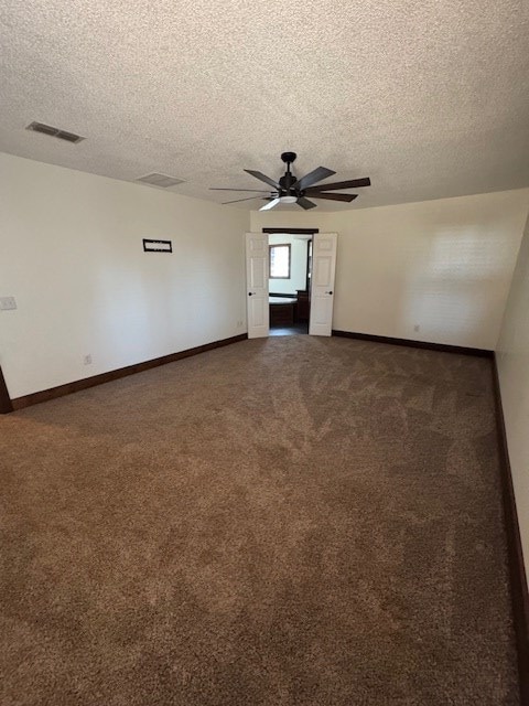 empty room with dark colored carpet, a textured ceiling, and ceiling fan