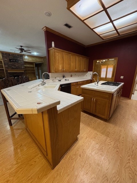 kitchen featuring kitchen peninsula, ceiling fan, sink, tile countertops, and a center island