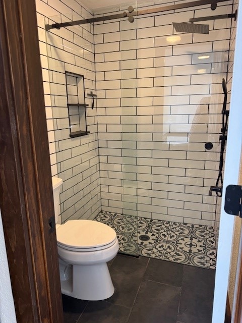 bathroom with tile patterned floors, toilet, and tiled shower