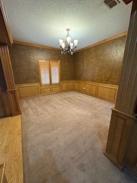 empty room featuring carpet flooring, crown molding, a textured ceiling, and an inviting chandelier