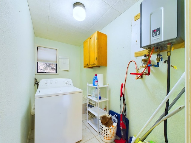 clothes washing area with water heater, light tile patterned floors, cabinets, and washer / dryer