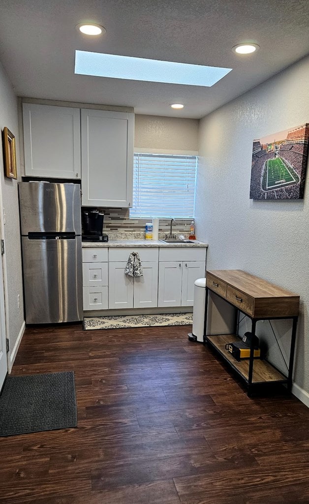 kitchen featuring stainless steel fridge, dark hardwood / wood-style flooring, white cabinetry, and sink