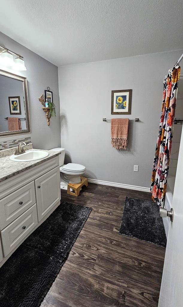 full bathroom featuring toilet, vanity, a textured ceiling, and hardwood / wood-style flooring