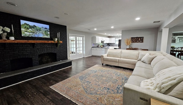 living room with dark hardwood / wood-style flooring, french doors, and a brick fireplace