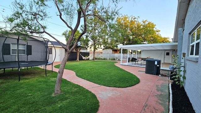 view of yard featuring cooling unit, a trampoline, and a patio