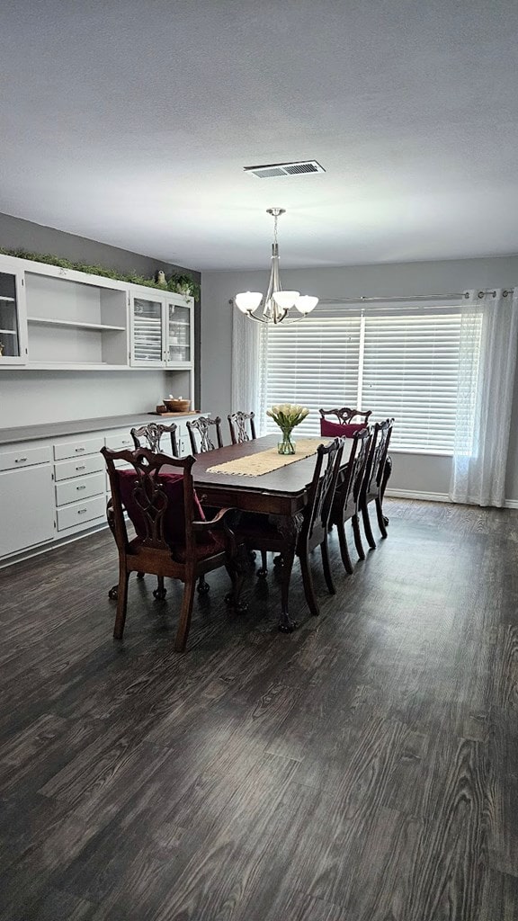 dining room with dark hardwood / wood-style floors, a textured ceiling, and an inviting chandelier