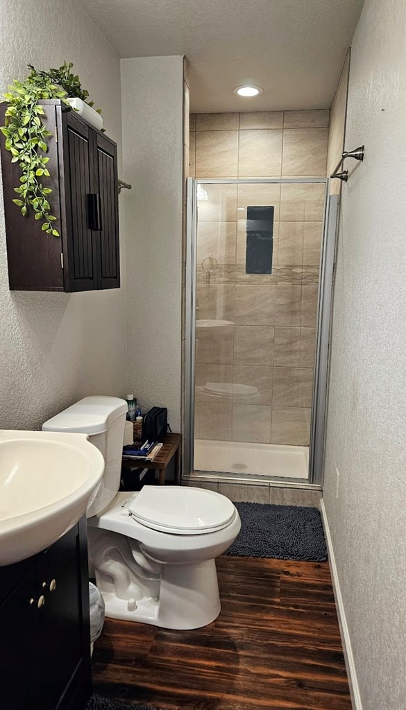 bathroom featuring walk in shower, vanity, wood-type flooring, and toilet