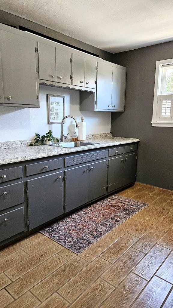 kitchen with hardwood / wood-style floors, gray cabinets, and sink