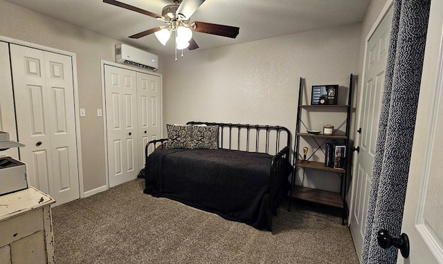 bedroom with two closets, ceiling fan, carpet floors, and a wall mounted air conditioner