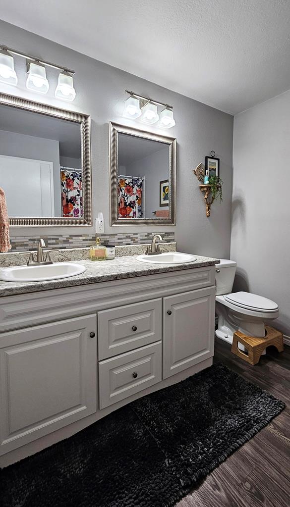 bathroom with a shower with curtain, wood-type flooring, a textured ceiling, toilet, and vanity