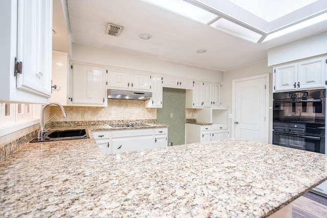 kitchen featuring white cabinets, backsplash, black appliances, and sink