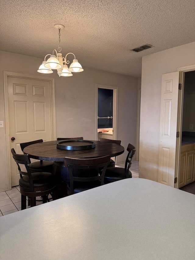 tiled dining space featuring a chandelier and a textured ceiling