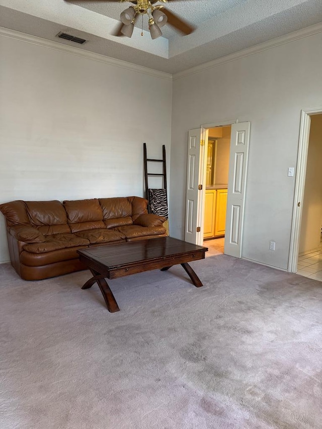 living room featuring a textured ceiling, light colored carpet, ornamental molding, and ceiling fan