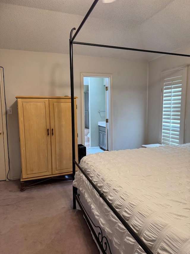 bedroom with connected bathroom, dark carpet, and a textured ceiling