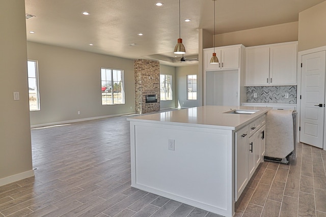 kitchen with a fireplace, backsplash, white cabinets, and wood tiled floor