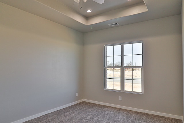 unfurnished room featuring recessed lighting, visible vents, baseboards, a tray ceiling, and dark carpet