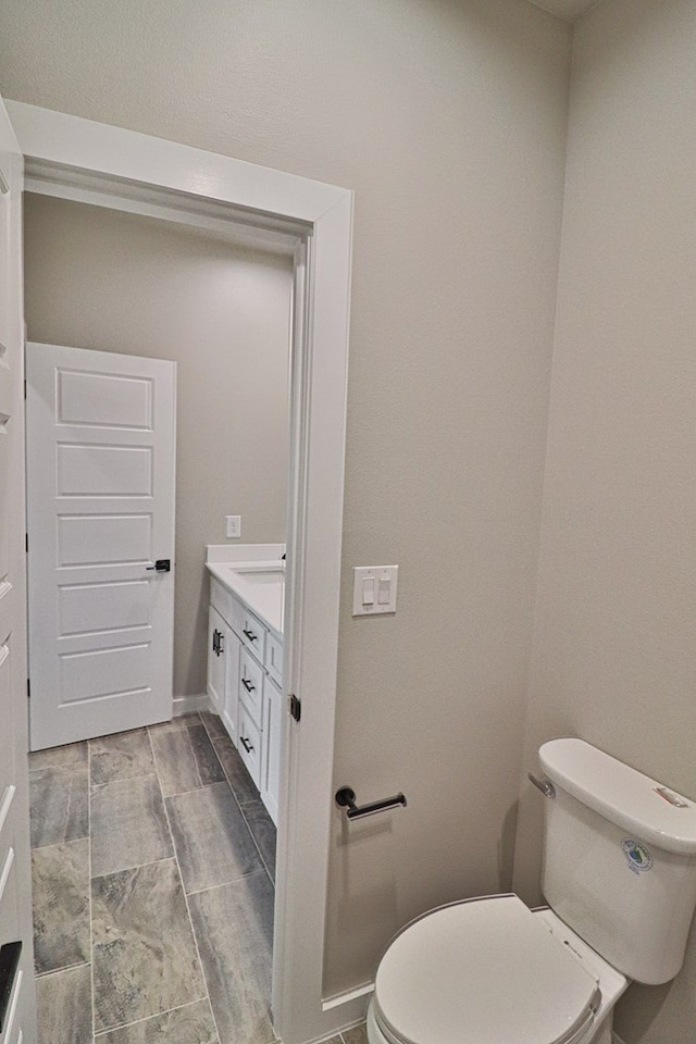 bathroom featuring vanity, toilet, and baseboards