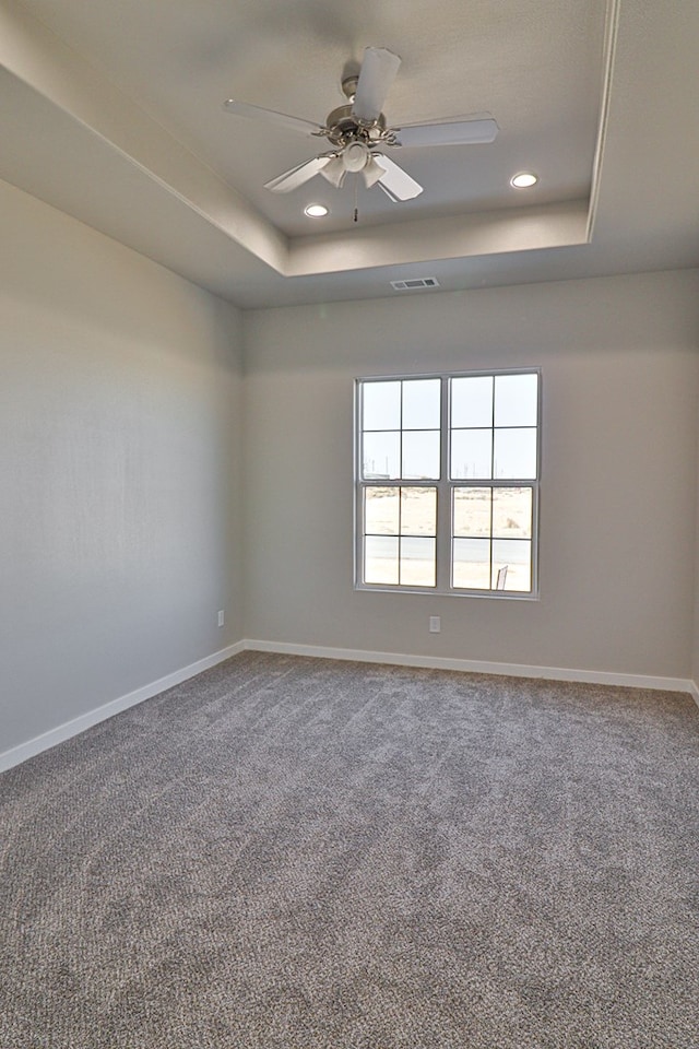 unfurnished room with ceiling fan, baseboards, visible vents, and a raised ceiling