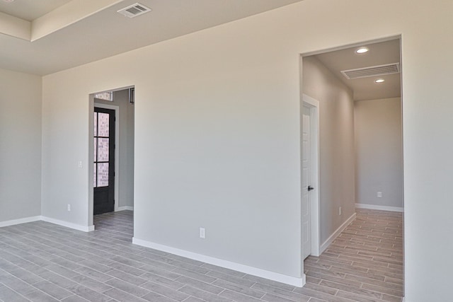 spare room with wood finish floors, visible vents, and baseboards