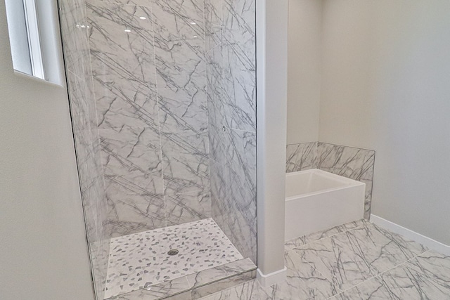 bathroom with a stall shower, marble finish floor, a garden tub, and baseboards