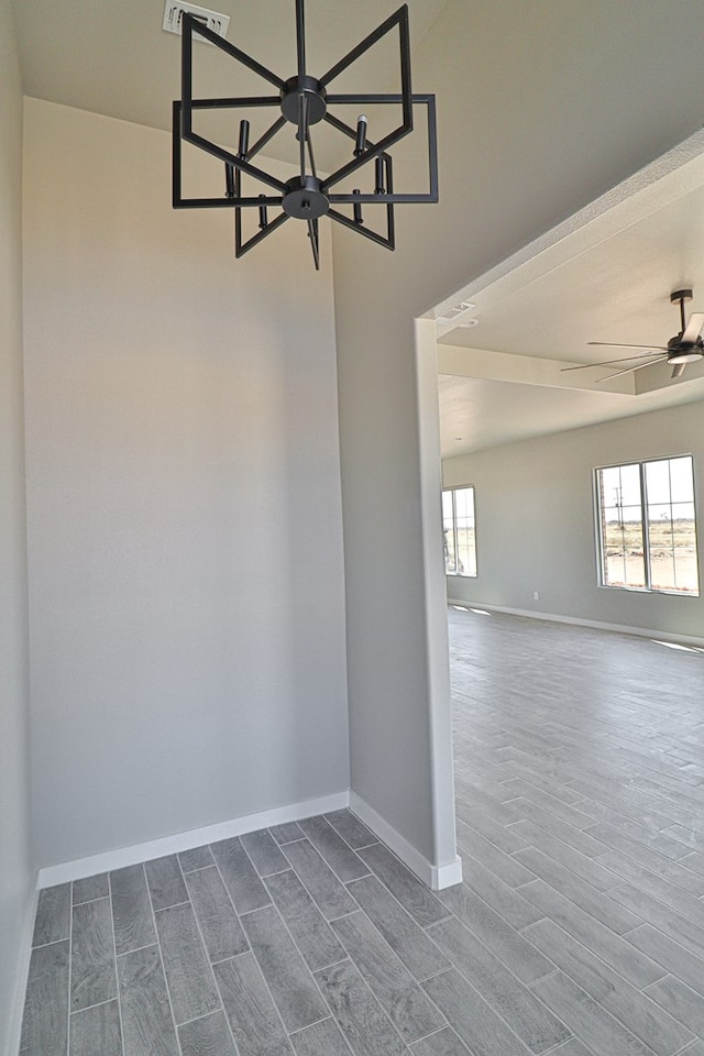 empty room with wood finish floors, a ceiling fan, and baseboards