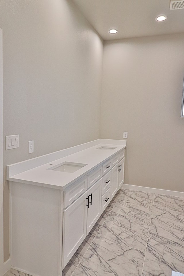 bathroom with marble finish floor, baseboards, a sink, and recessed lighting