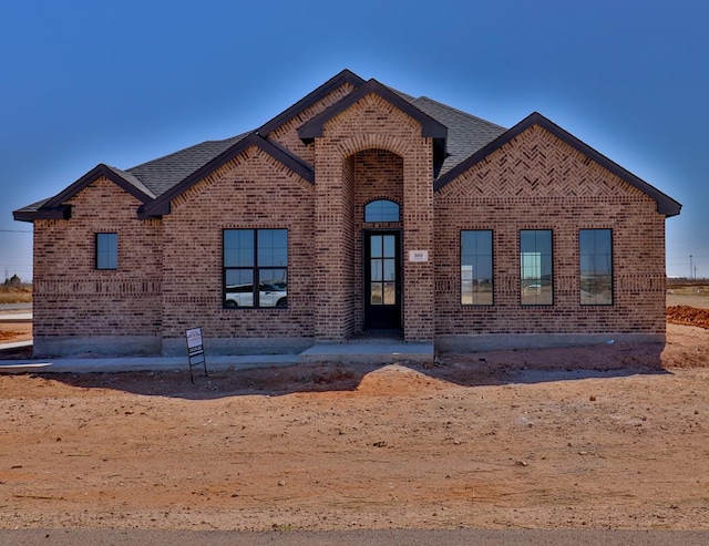 view of front of property with brick siding and a shingled roof