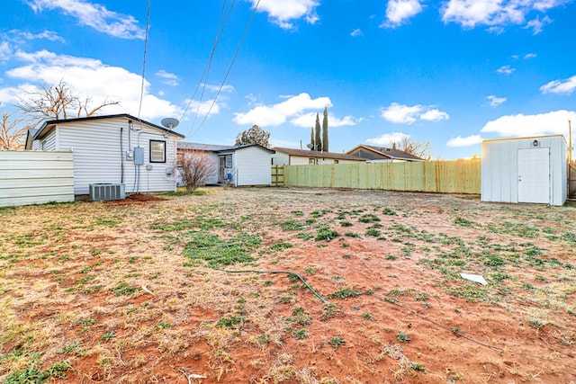 view of yard with an outdoor structure, fence, central AC unit, and a storage unit