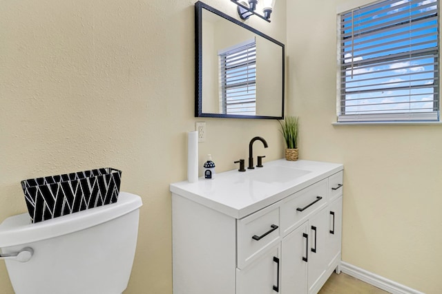 bathroom with toilet, baseboards, and vanity